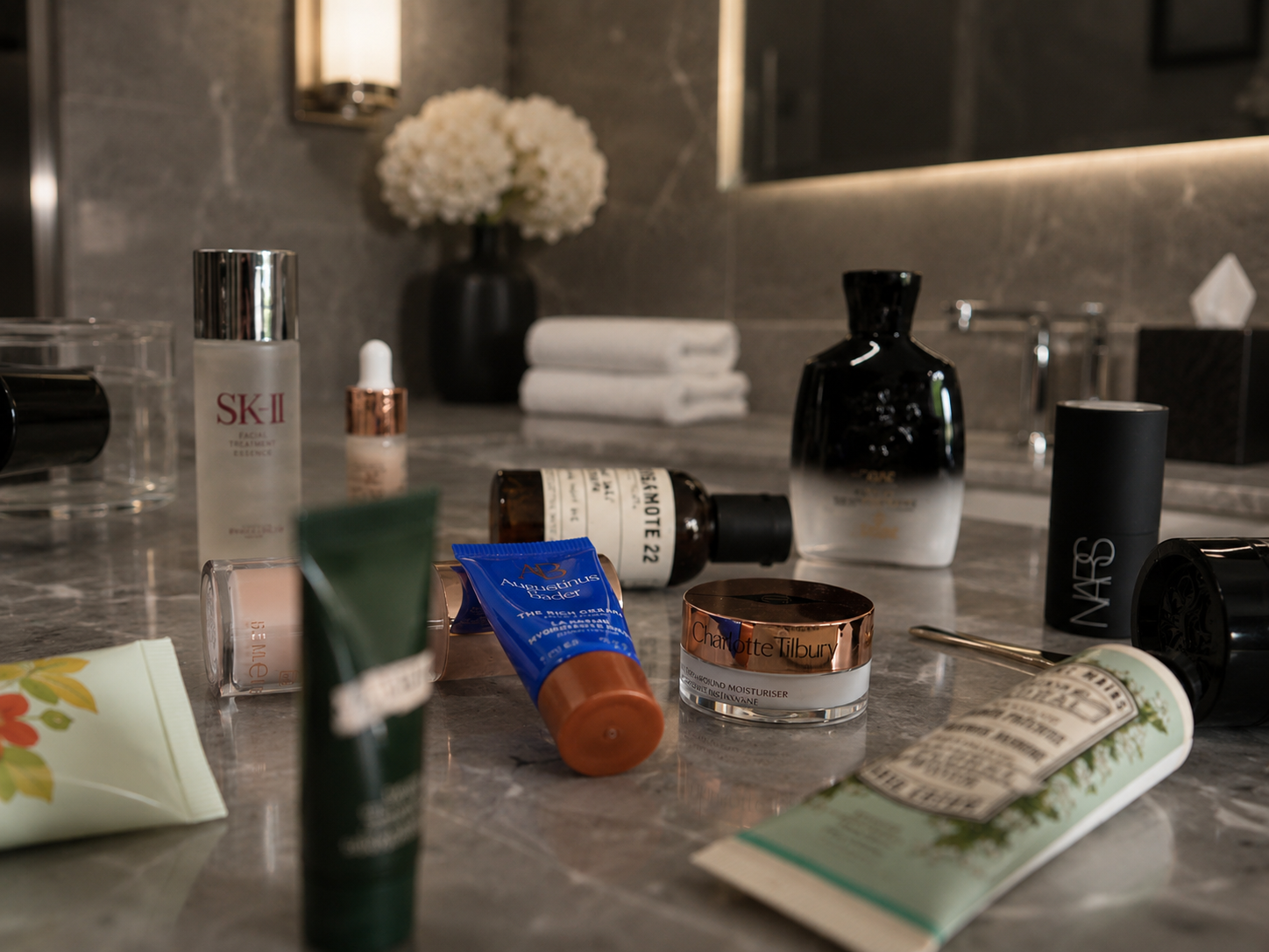 Luxury skincare and wellness travel essentials styled in a dark spa-inspired hotel bathroom setting