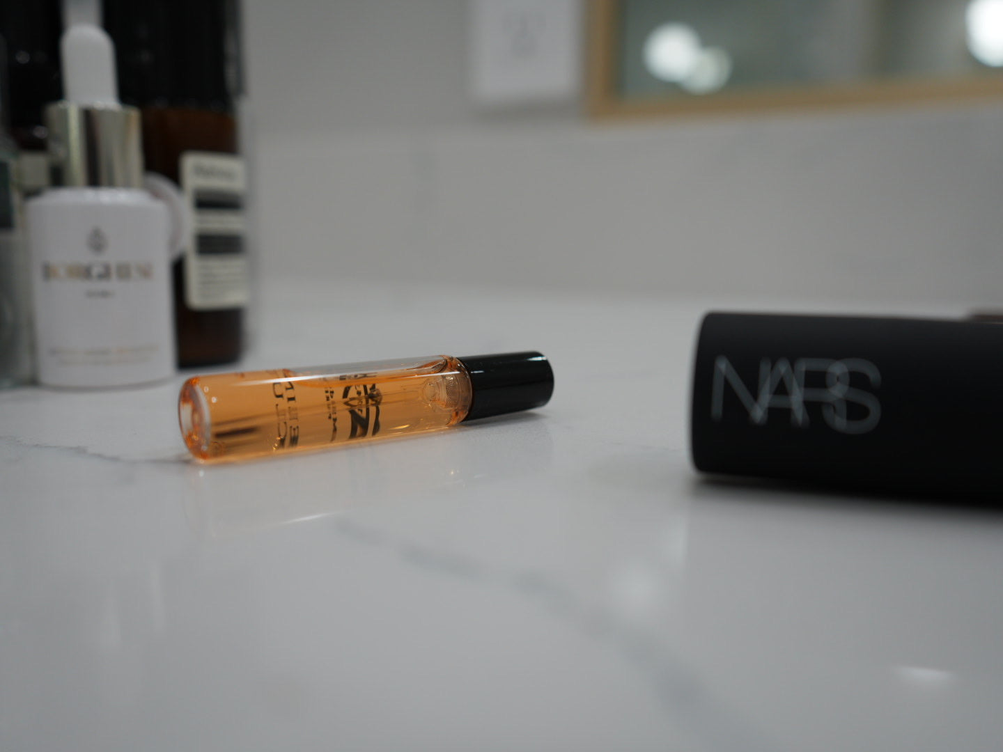 Luxury fragrance and beauty detail shot featuring travel-ready cosmetics styled on a marble vanity