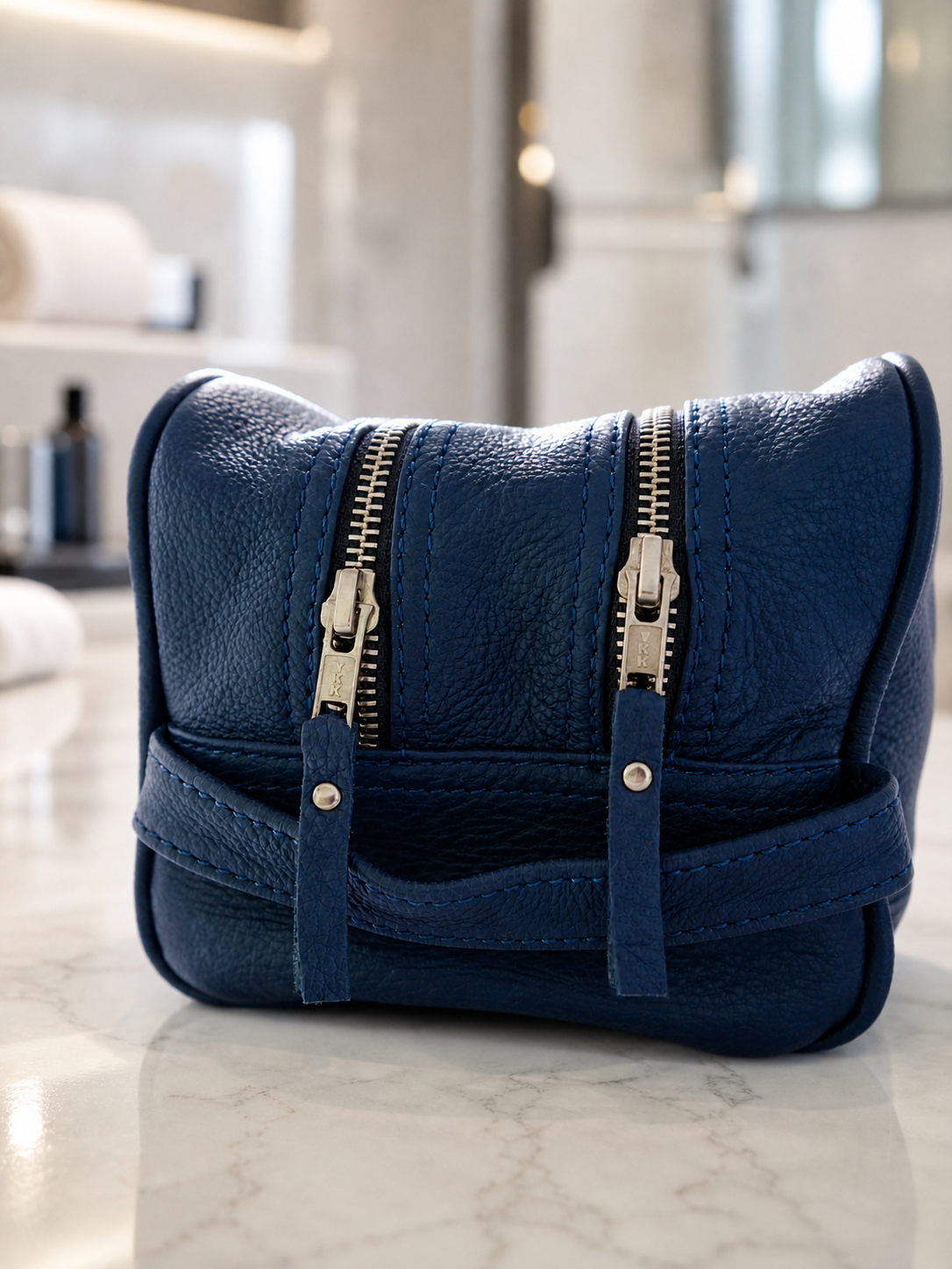 Blue leather travel bag from the TILI Tom collection displayed in a bright luxury setting